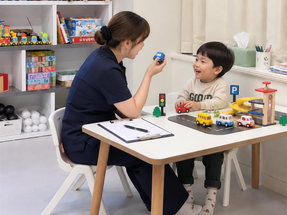 열매아동발달연구소 위례점 치료실에서 선생님과 아이가 자동차 교구로 놀이하며 대화하는 언어재활 모습